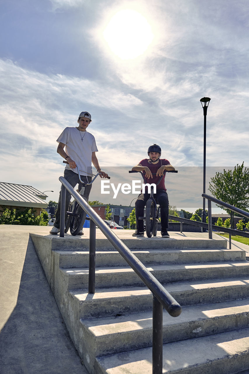 Portrait of riders with bmx bikes at skateboard park during sunny day