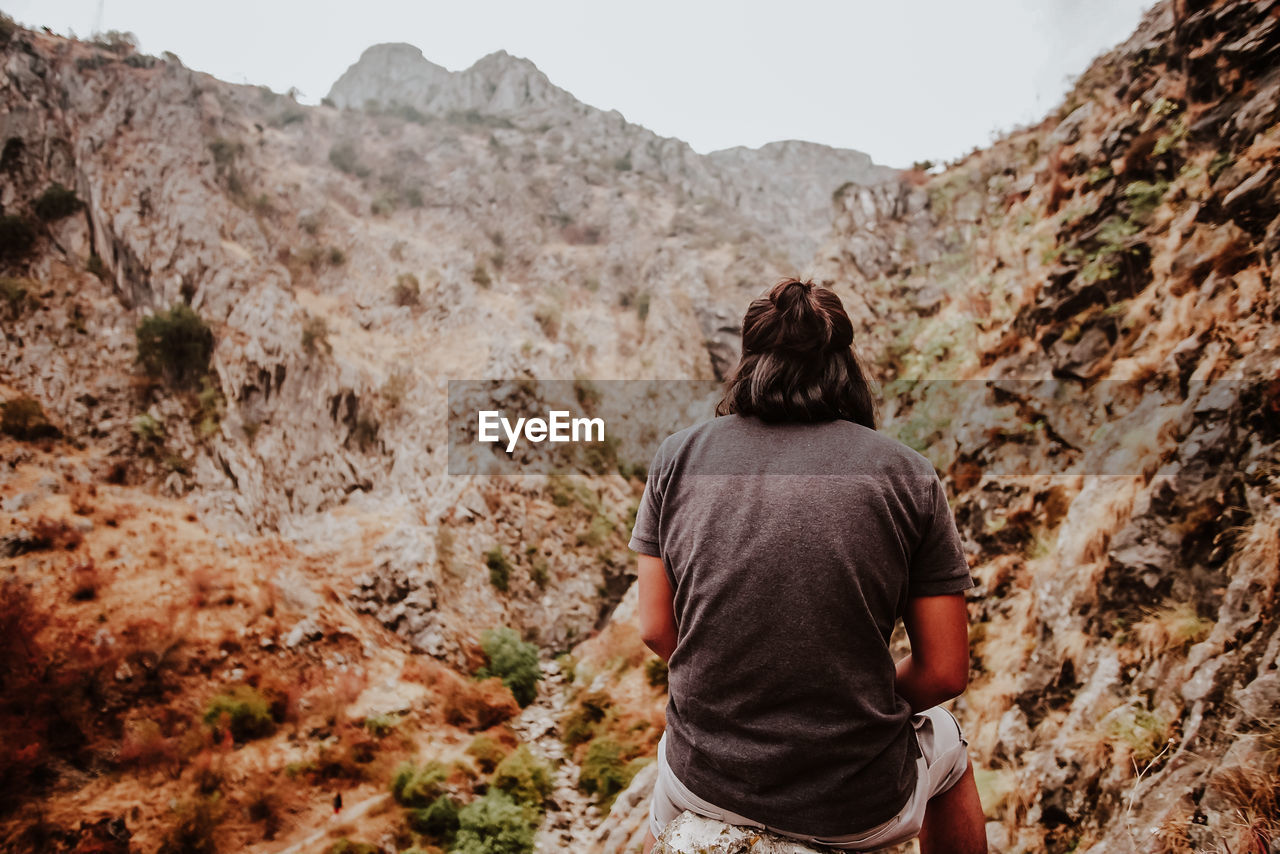 Rear view of man sitting against mountains