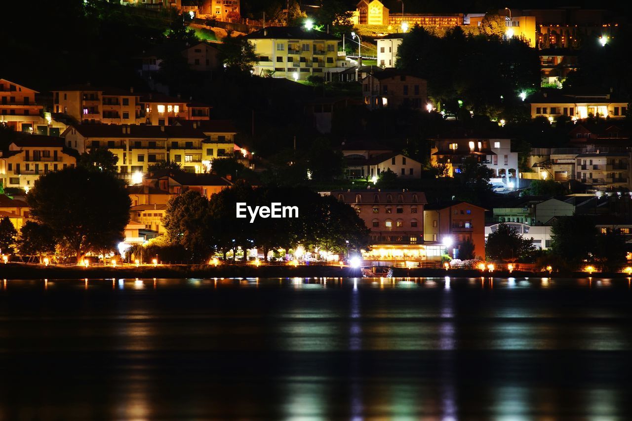 Illuminated cityscape by river at night