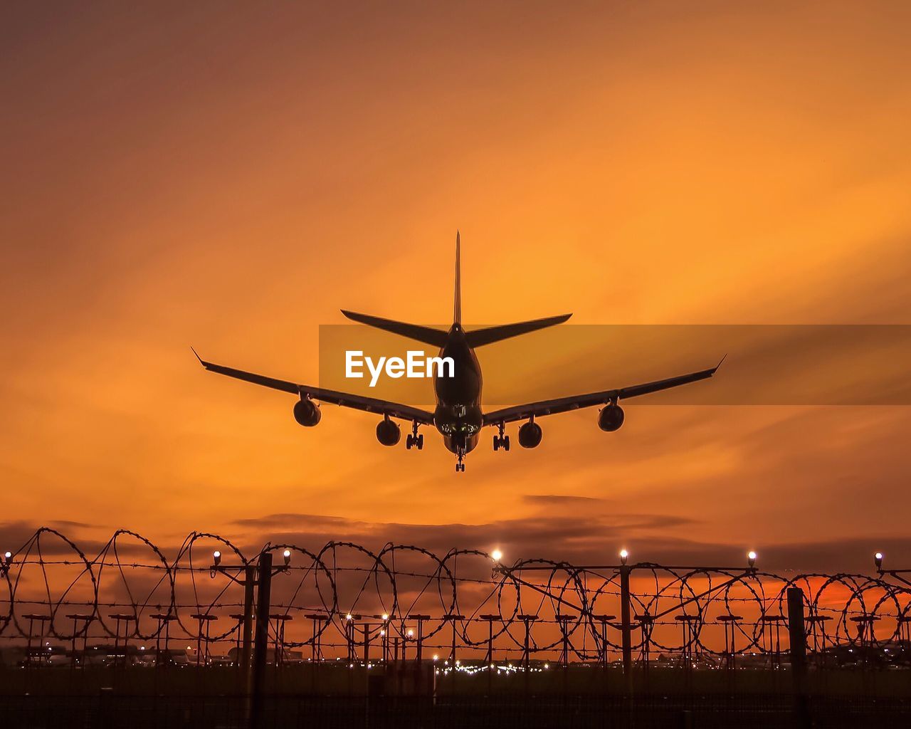 Low angle view of silhouette airplane flying against sky during sunset