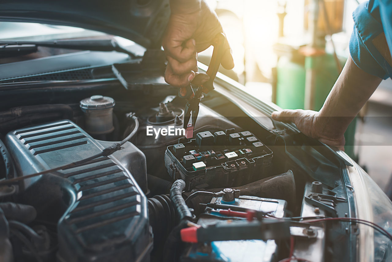 midsection of mechanic repairing car engine