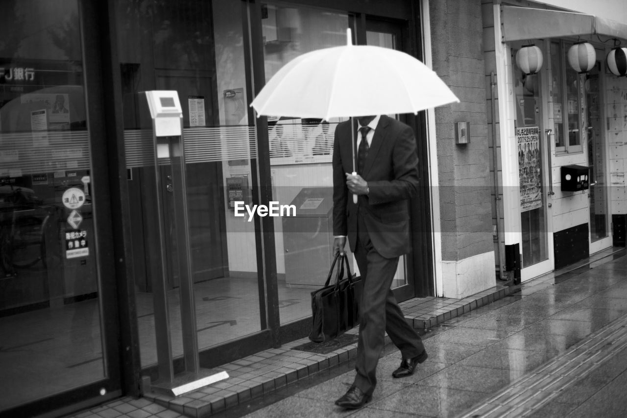 FULL LENGTH OF MAN WITH UMBRELLA WALKING IN BUILDING