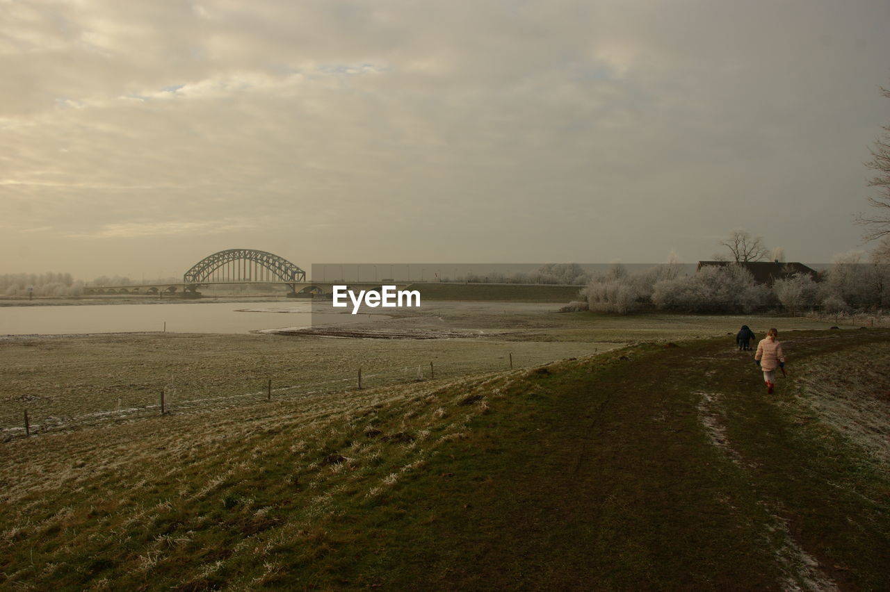 SCENIC VIEW OF PERSON WALKING ON BRIDGE AGAINST SKY