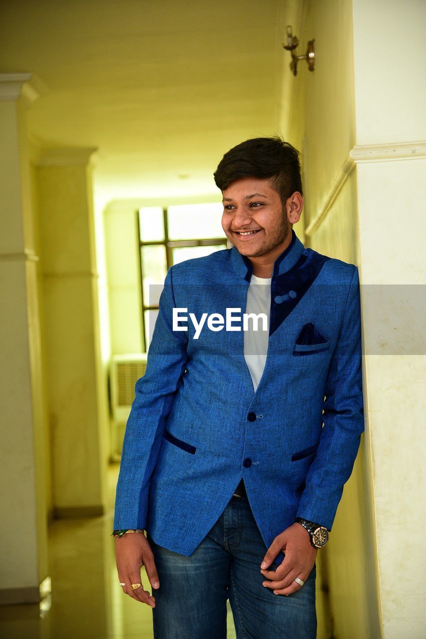 Smiling young man standing in corridor