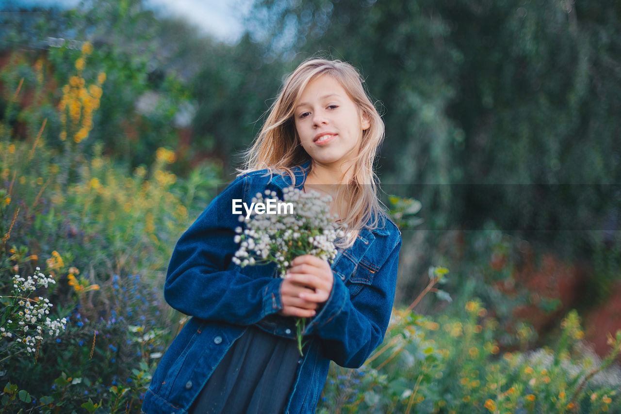 Portrait of young woman standing against plants