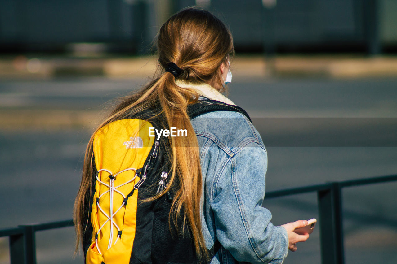 REAR VIEW OF WOMAN STANDING ON RAILING