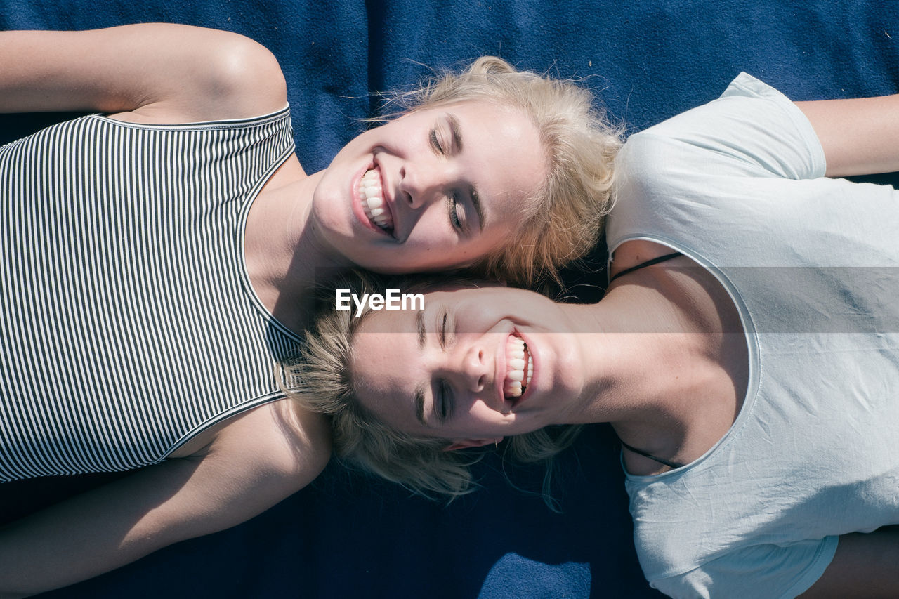 High angle view of smiling friends lying on bed