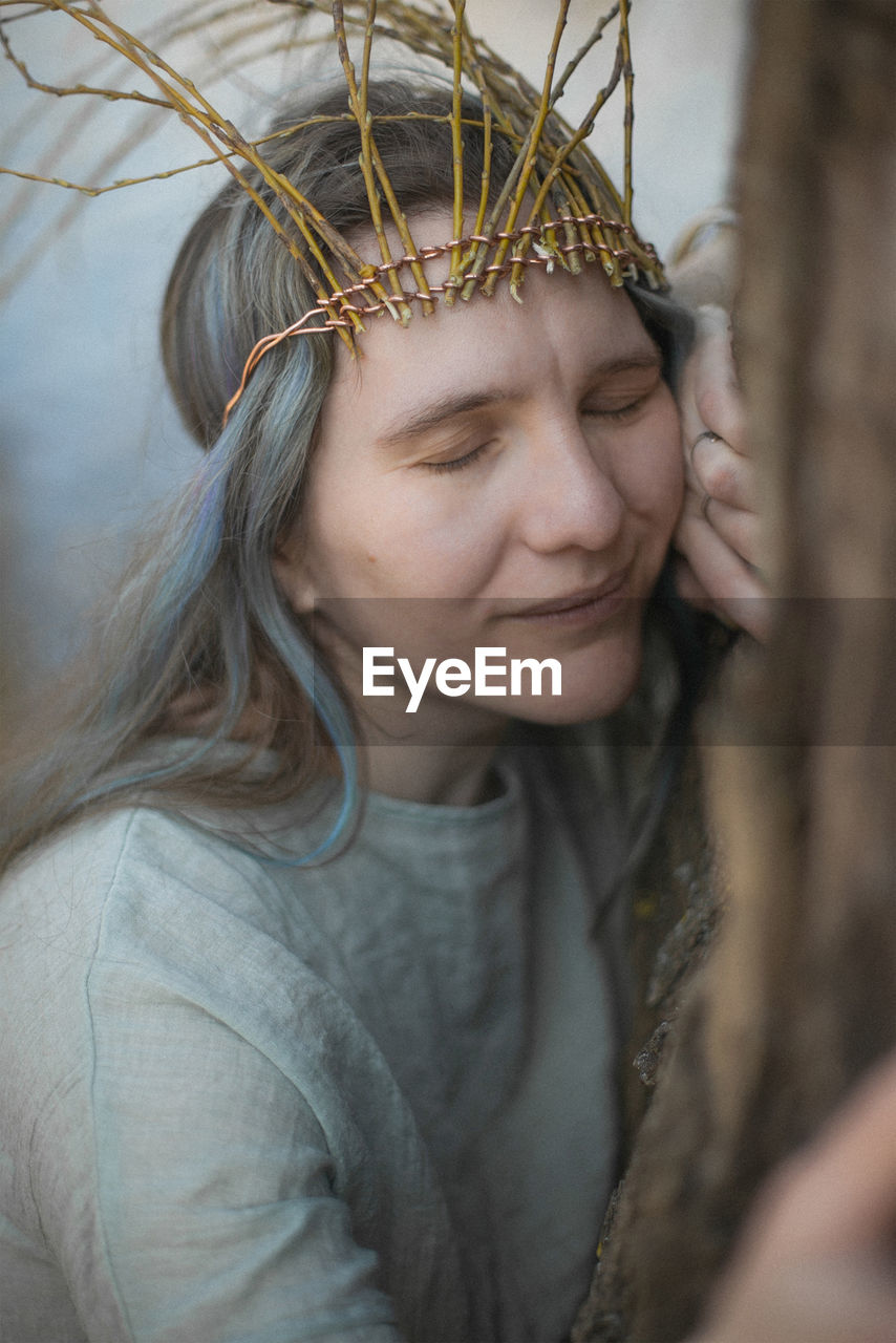 Close up celtic styled woman hugging tree with relieved smile portrait picture