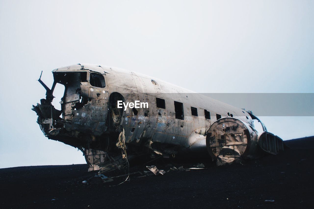 Abandoned airplane at beach against sky