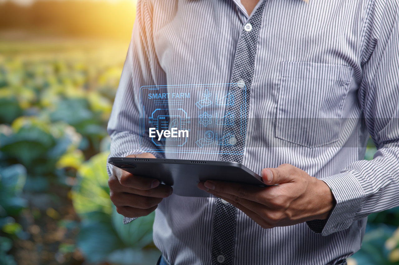 one person, adult, technology, wireless technology, midsection, holding, communication, business, digital tablet, men, standing, shirt, occupation, nature, computer, growth, front view, using computer, computer network, internet, outdoors, portability, businessman, spring, button down shirt, agriculture, rural scene, day, business finance and industry, working, casual clothing, screen, landscape, young adult, plant