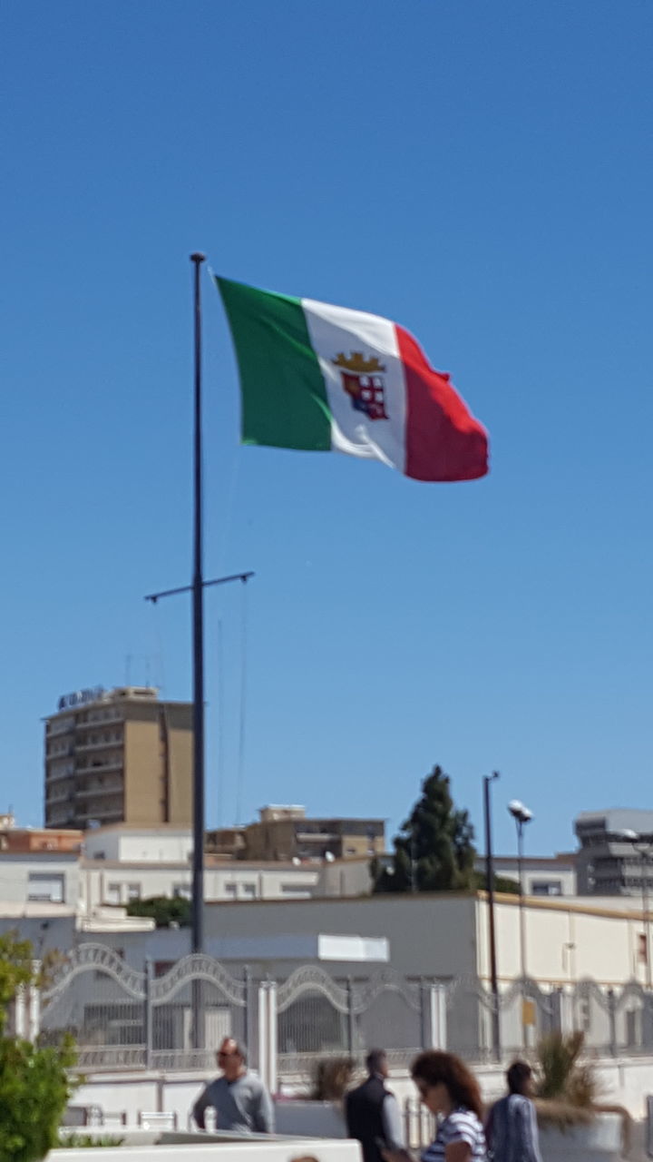 LOW ANGLE VIEW OF FLAG AGAINST CLEAR BLUE SKY