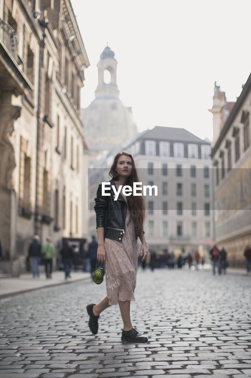 Full length of woman walking on street against buildings in city