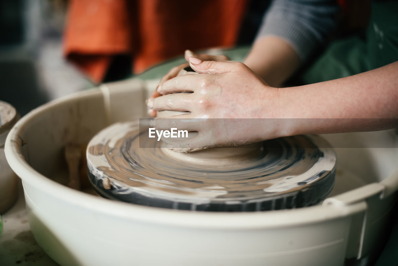 Woman hands moulding ceramic piece on potters wheel