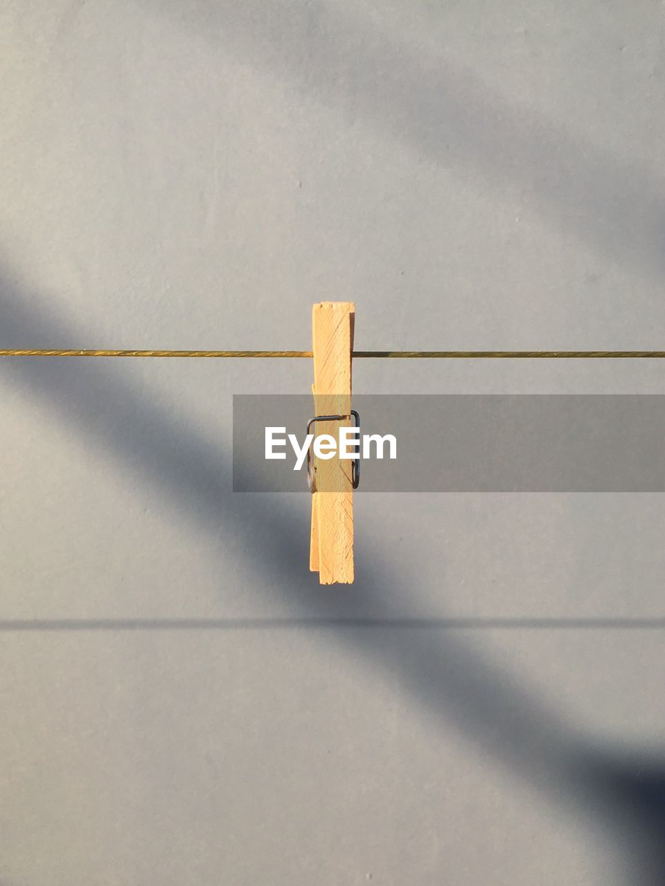 Close-up of clothespin hanging on clothesline against wall