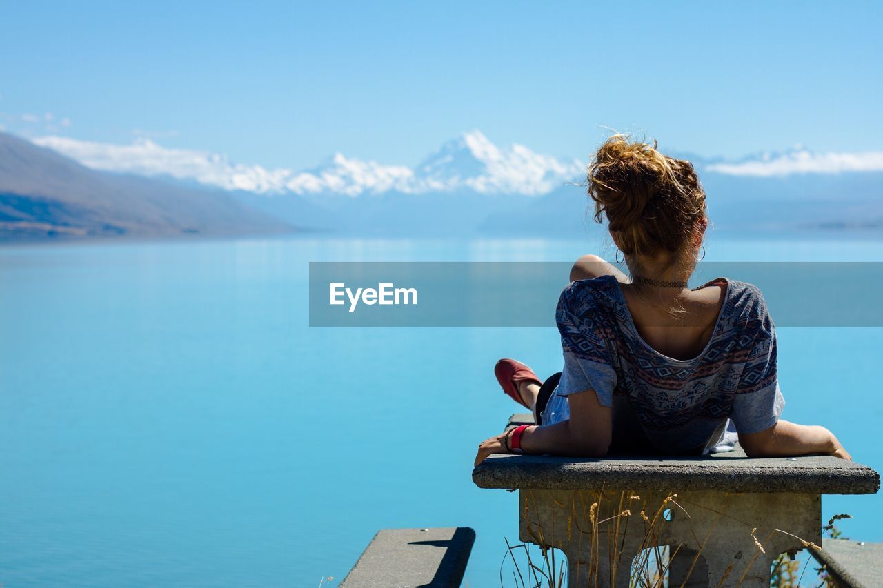 Rear view of woman looking at lake during summer