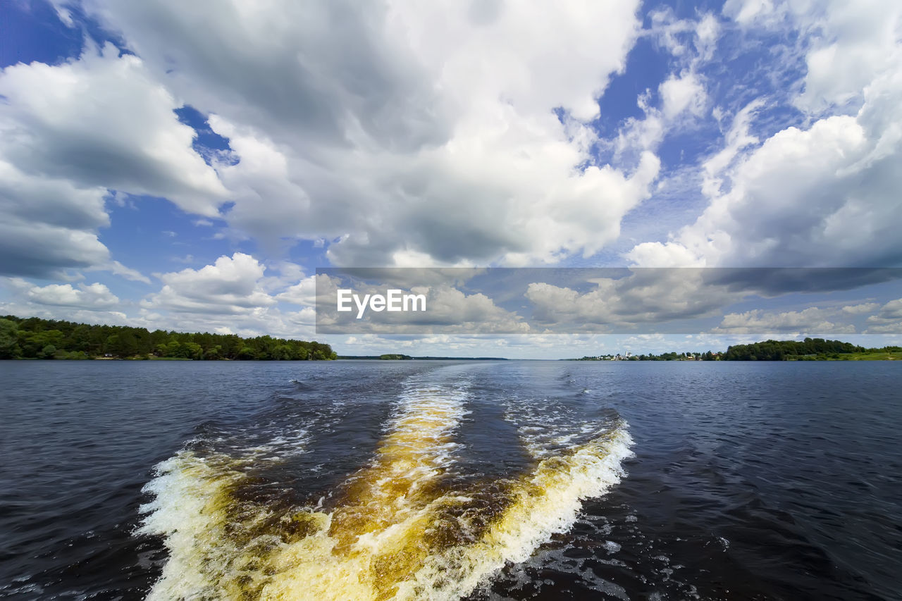Trace on the water from the movement of the boat. volga river. blue sky with white clouds. 