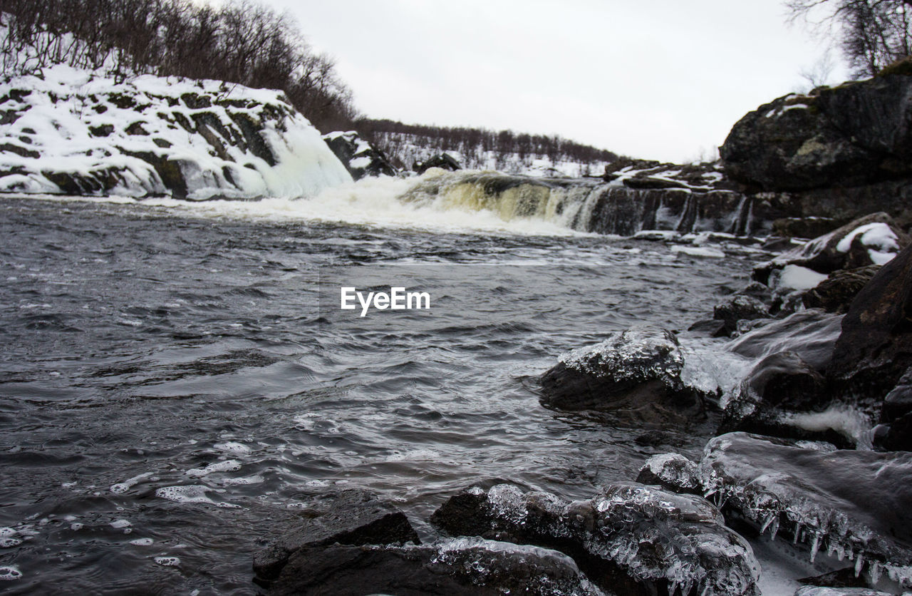 Scenic view of waterfall by sea against sky
