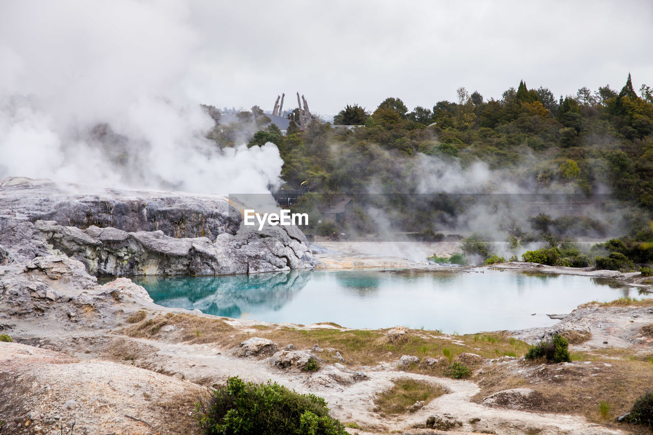 Scenic view of hot spring against cloudy sky