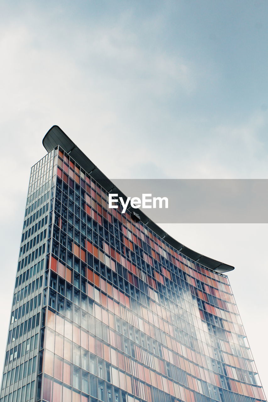 Low angle view of modern building against cloudy sky