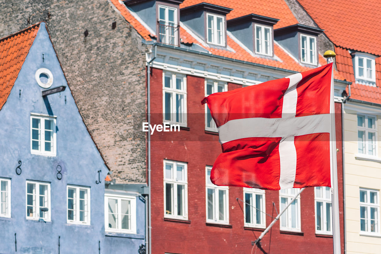 Old houses along the nyhavn canal or new harbour, entertainment district in copenhagen, danish flag