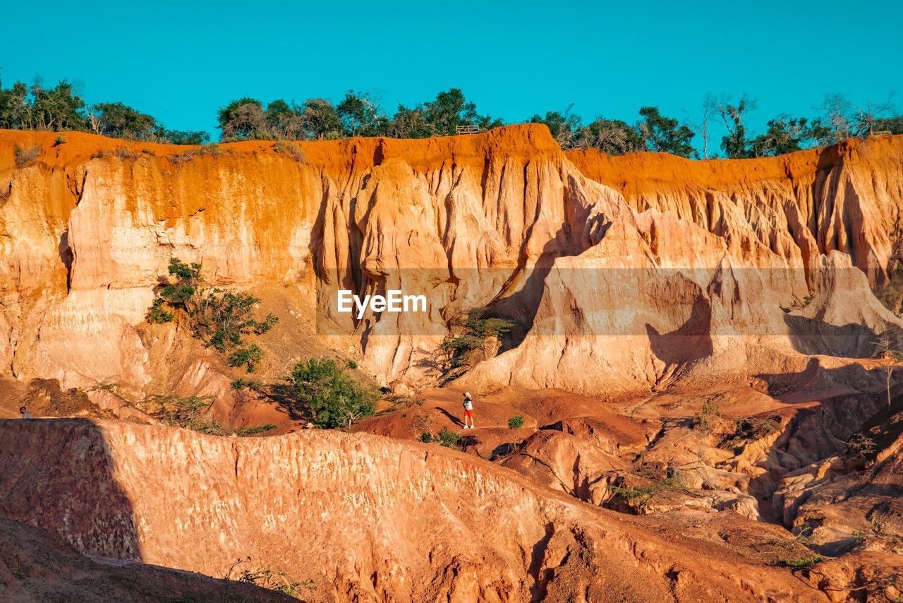 Tourist dwarfed by the rock formations at marafa depression - hell's kitchen at sunset in kenya