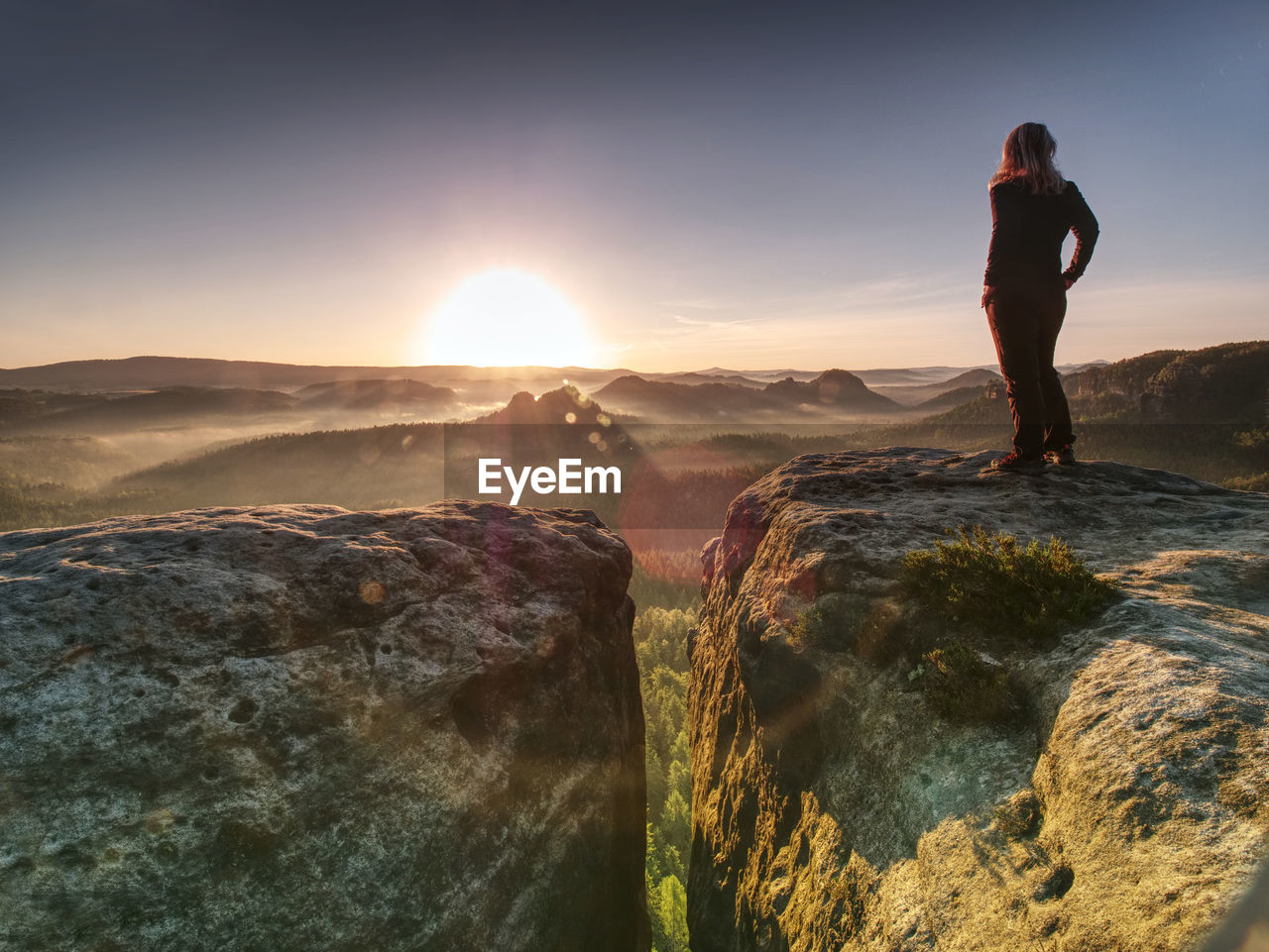 Alone woman hiker model in wild nature within marvelous sunrise. misty valley somewhere in hills