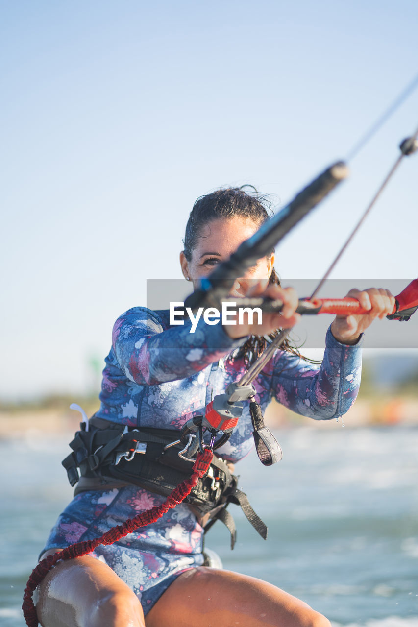 Side view of fit female kite surfer in swimsuit ridding waves in sea on sunny day in summer