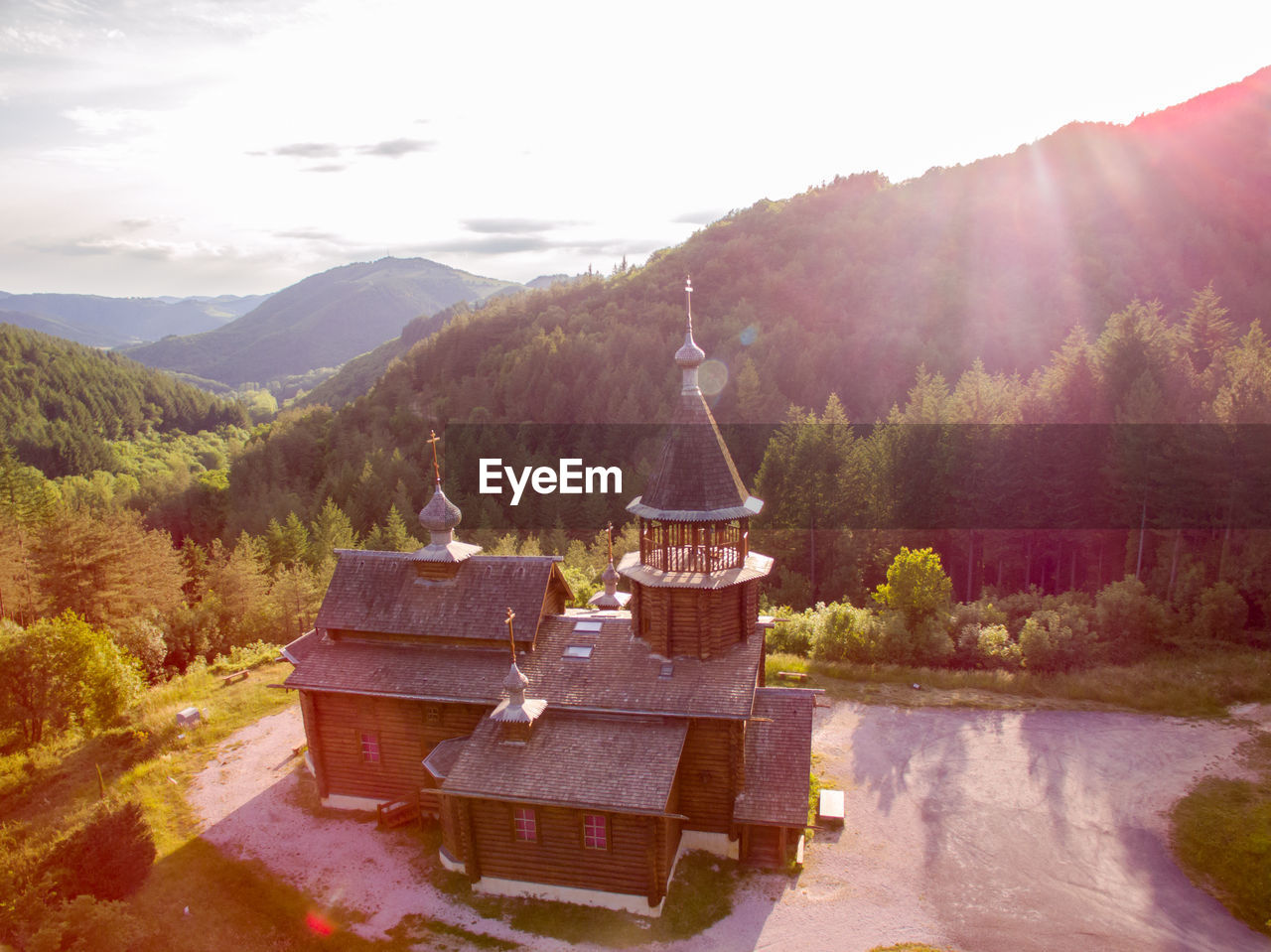 BUILT STRUCTURE BY TREES AGAINST MOUNTAINS