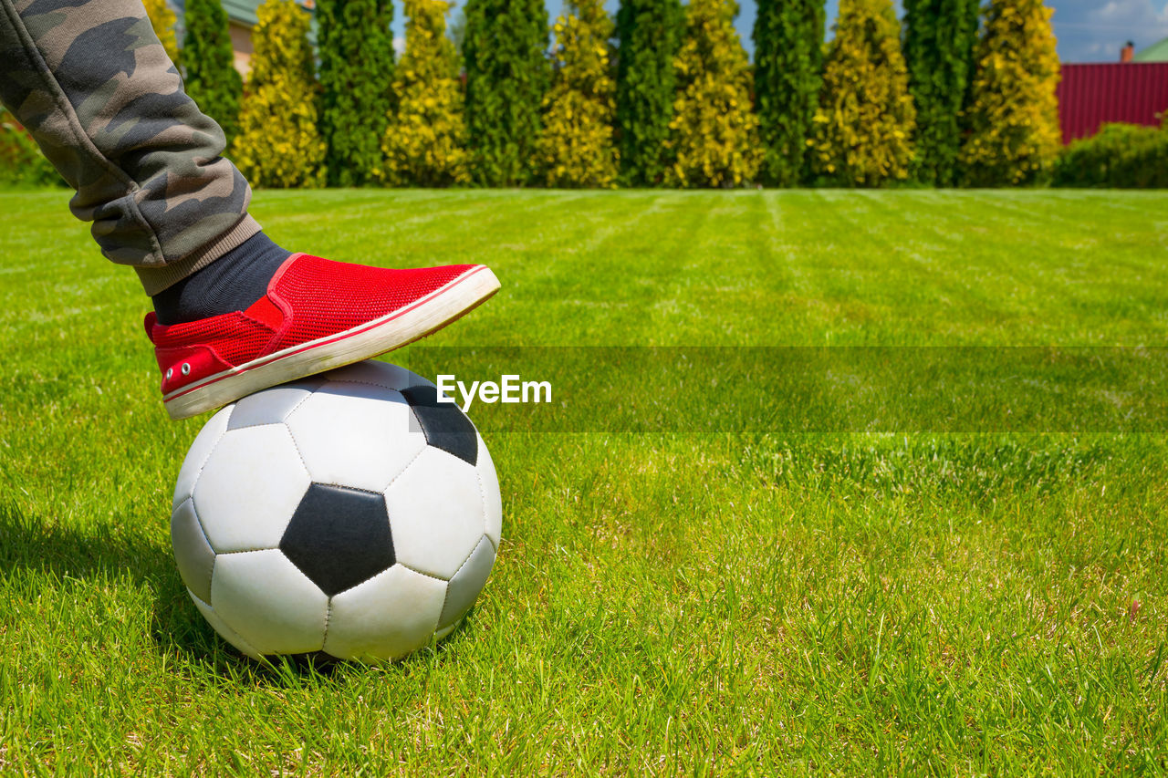 A football ball and child leg at the background of a house backyard on sunny day