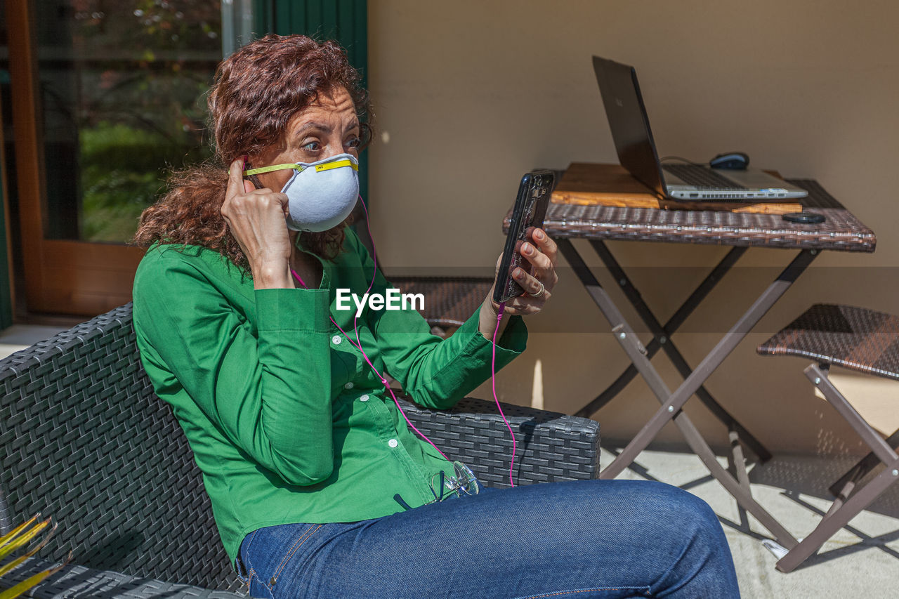 Woman using smart phone sitting on chair at home