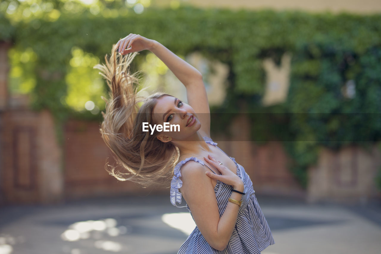 Portrait of smiling young woman tossing hair in park