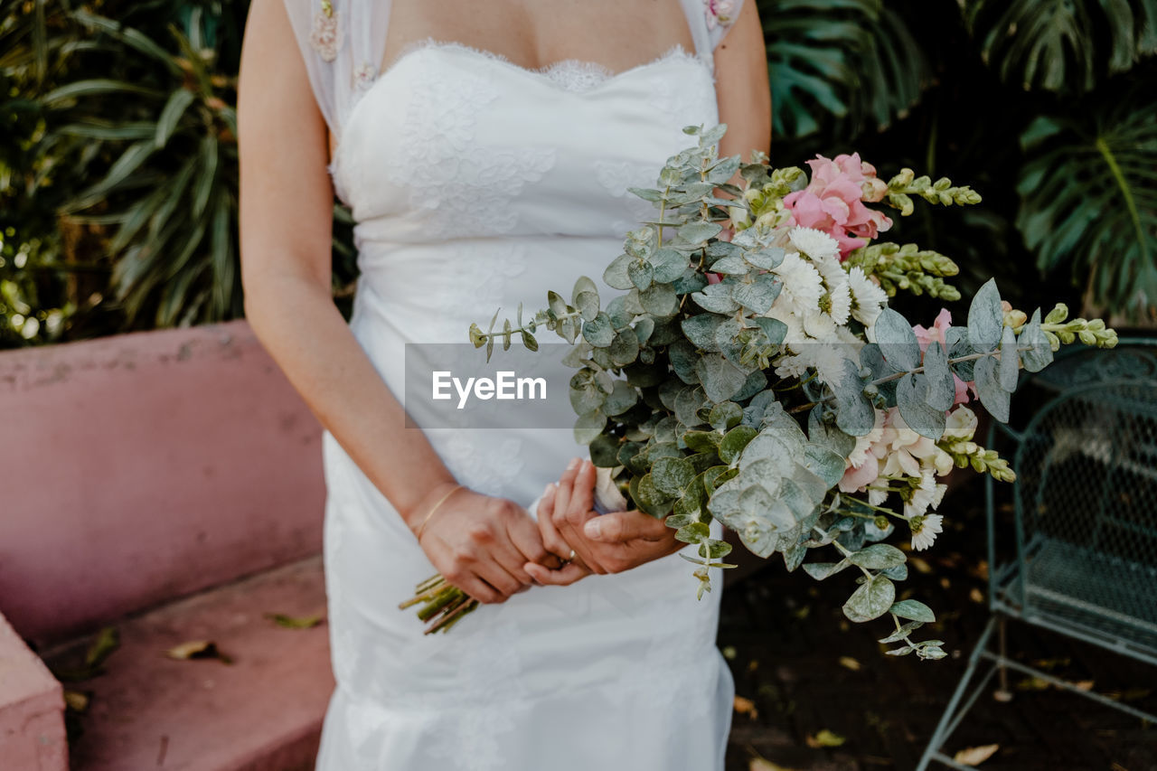 Midsection of bride holding bouquet