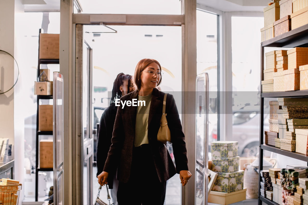 Smiling female friends entering retail store