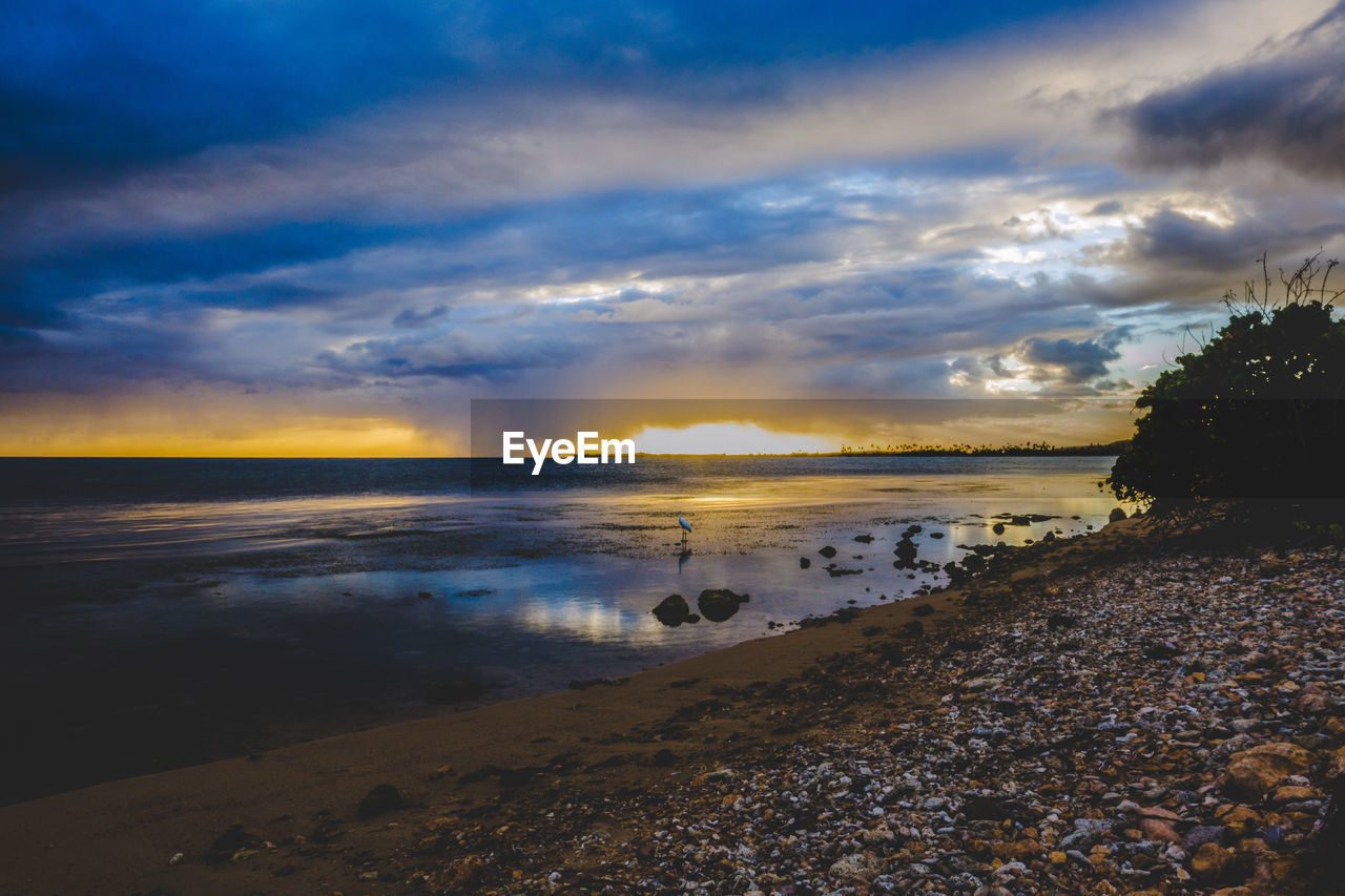 SCENIC VIEW OF BEACH AGAINST SKY AT SUNSET