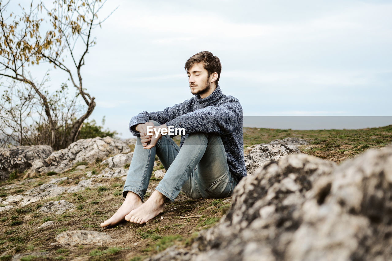 Portrait of young man sitting on rock