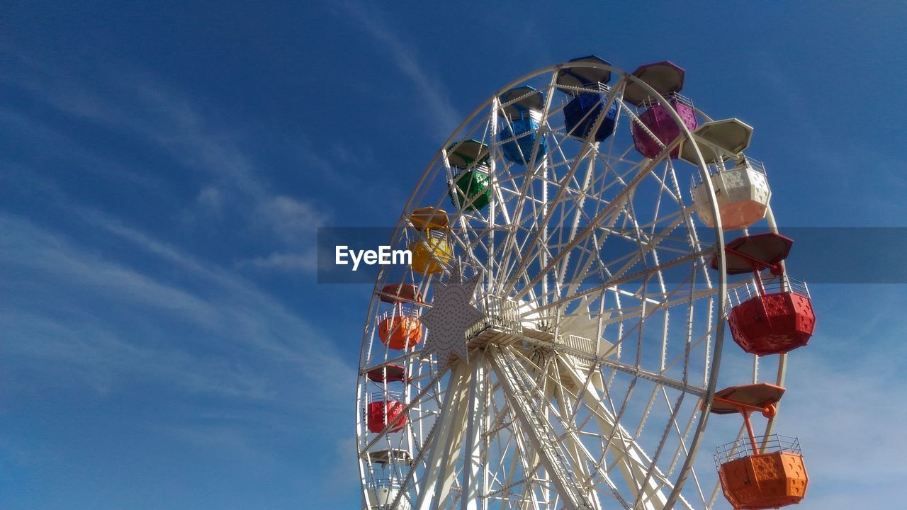 Low angle view of ferris wheel against blue sky