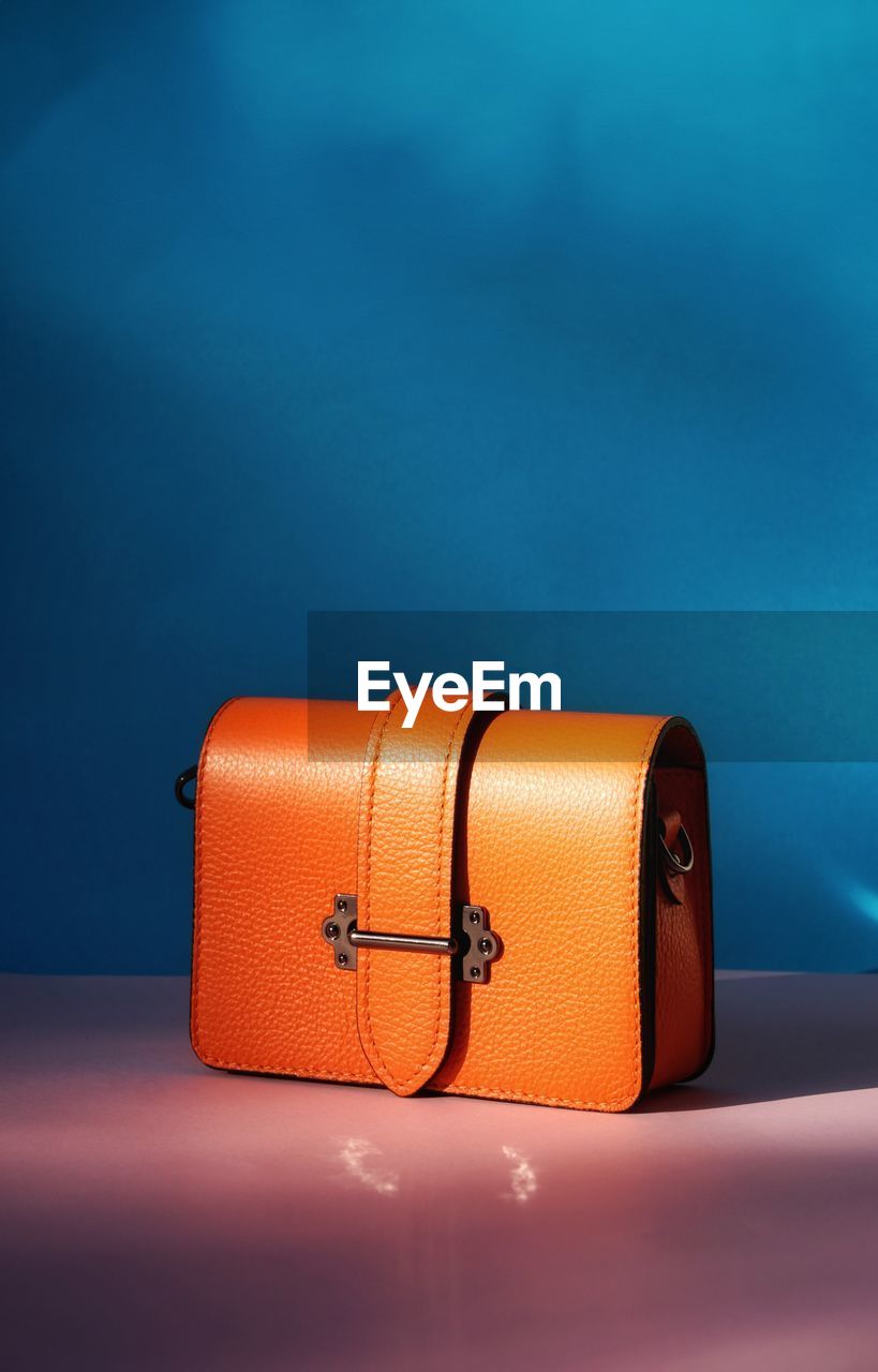 Orange color bag in front of blue background