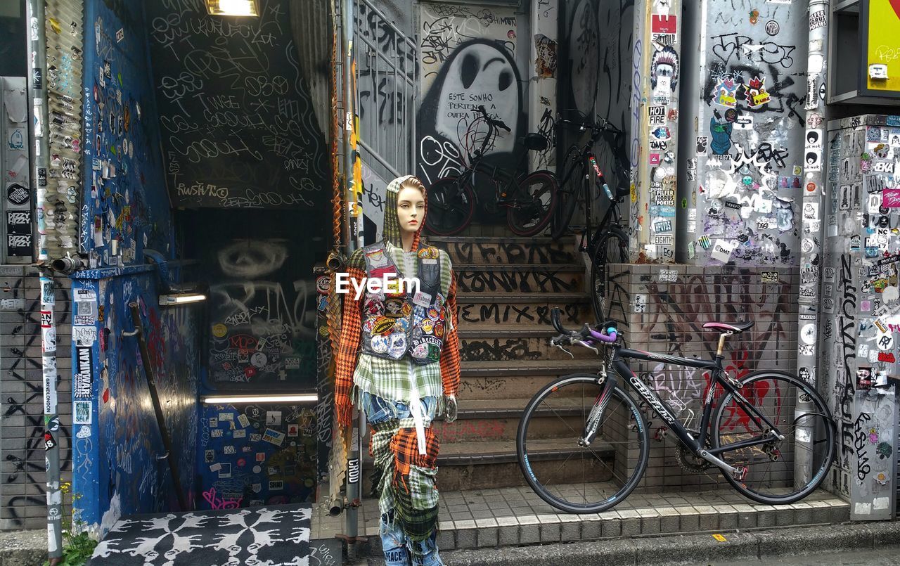 FULL LENGTH OF WOMAN STANDING BY GRAFFITI