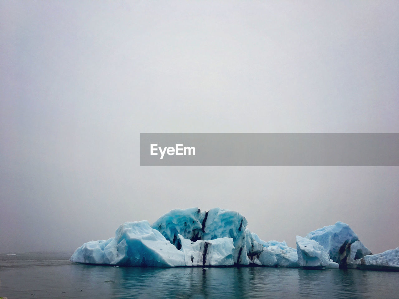 VIEW OF FROZEN LAKE AGAINST SKY