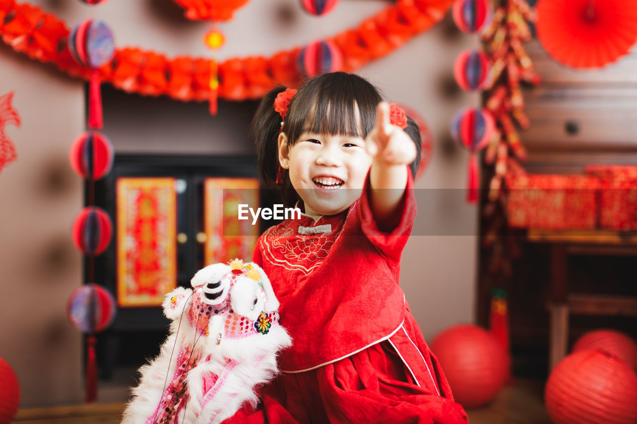 Portrait of smiling girl pointing at home