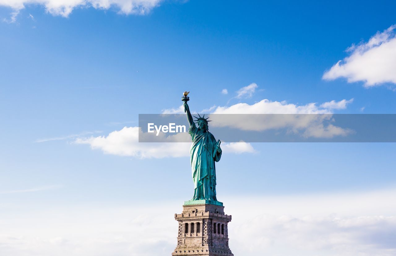 Low angle view of statue of liberty against cloudy sky