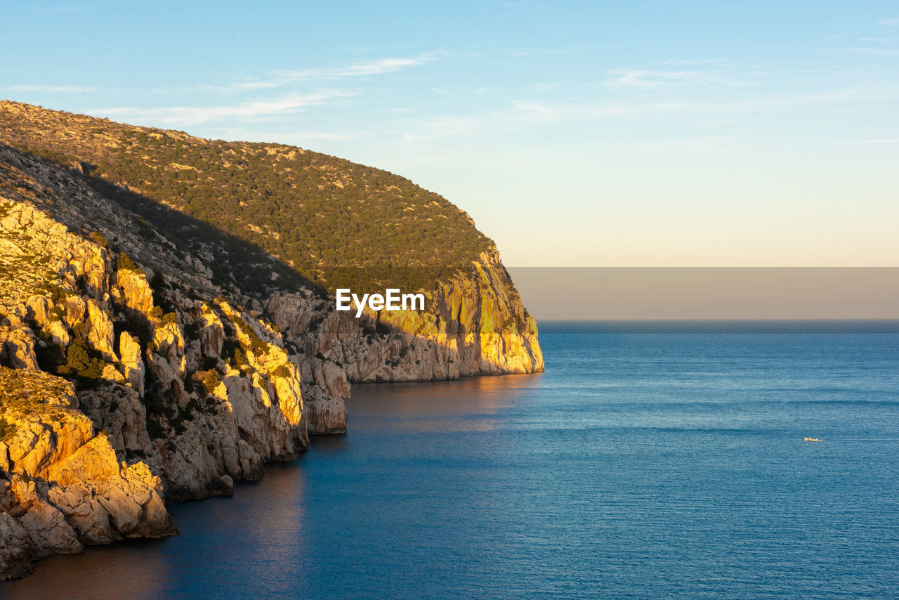 Scenic view of rocks by sea against sky