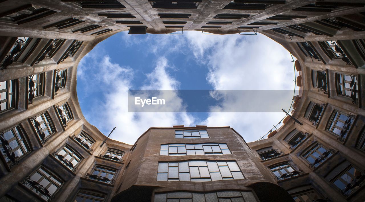 Directly below shot of buildings against cloudy sky