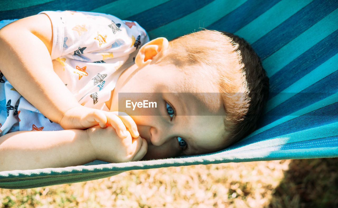 High angle portrait of baby boy lying on hammock in the sun