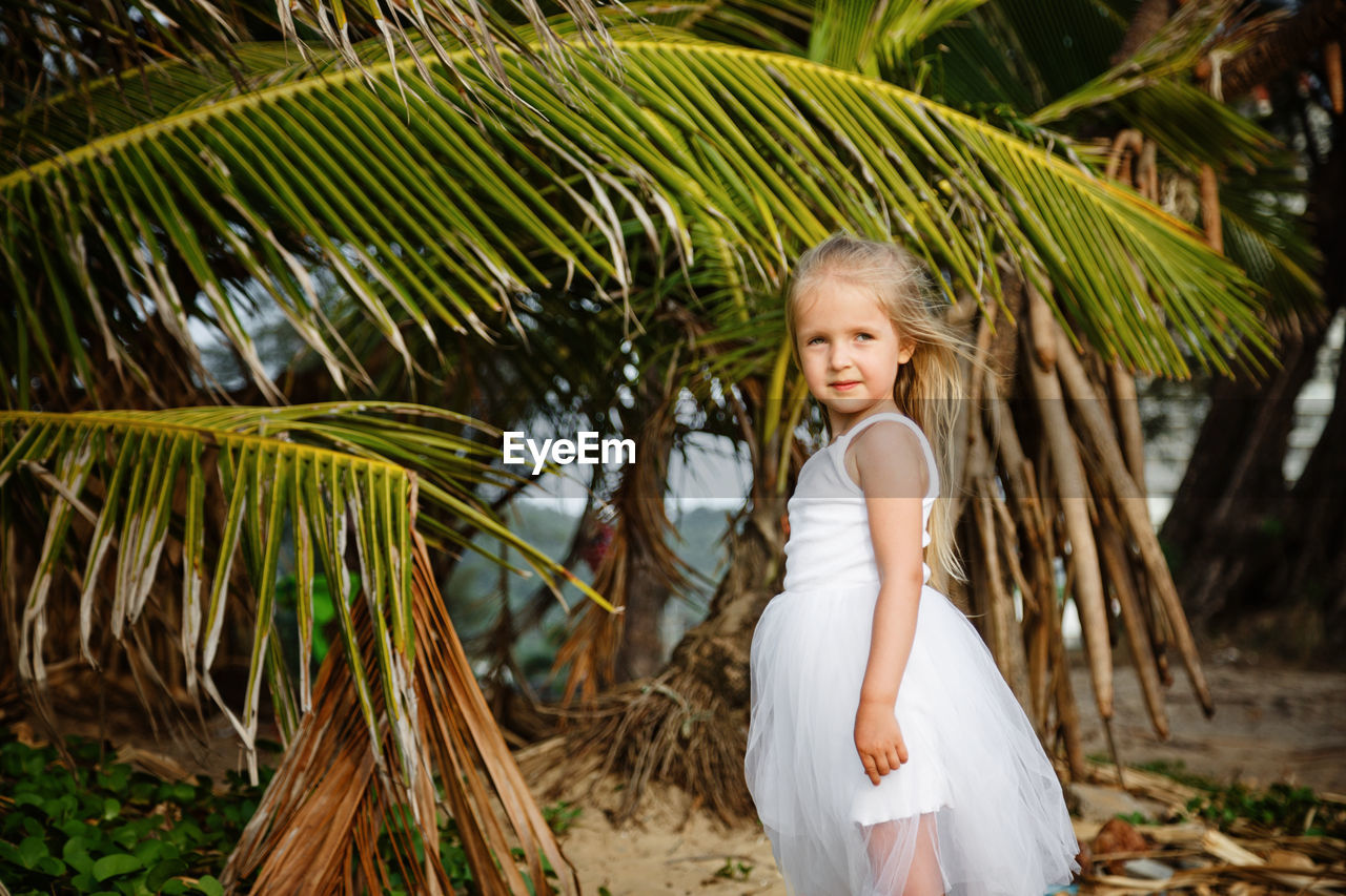 Girl standing against palm tree