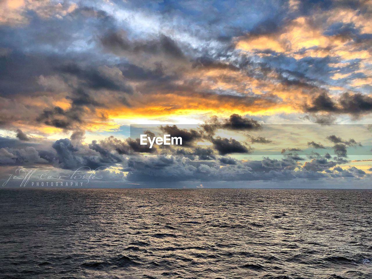 SCENIC VIEW OF SEA AGAINST CLOUDY SKY DURING SUNSET