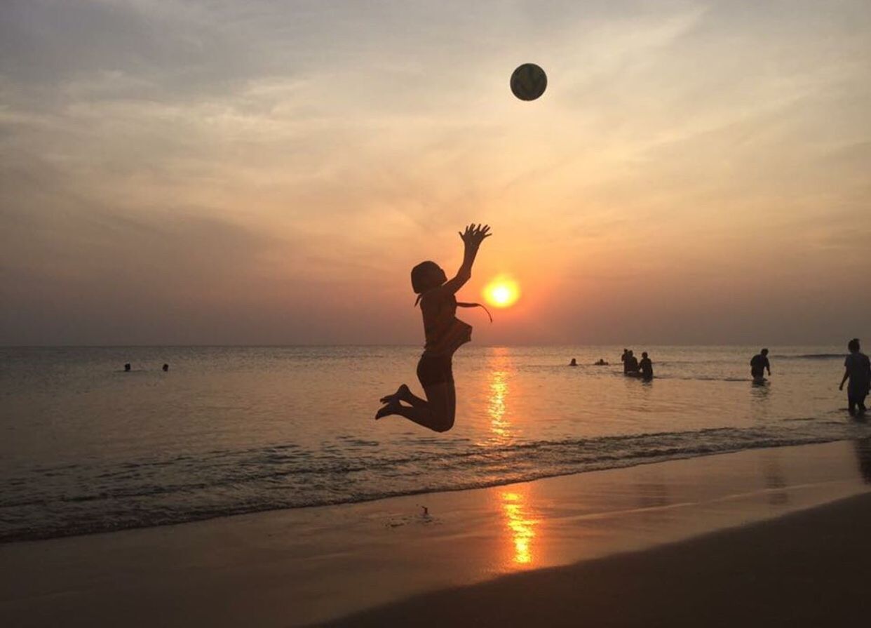 SILHOUETTE PEOPLE PLAYING WITH BALL IN BACKGROUND AT SUNSET