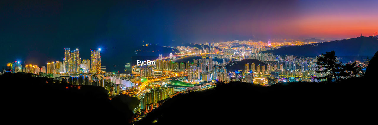 ILLUMINATED MODERN BUILDINGS AGAINST SKY AT NIGHT