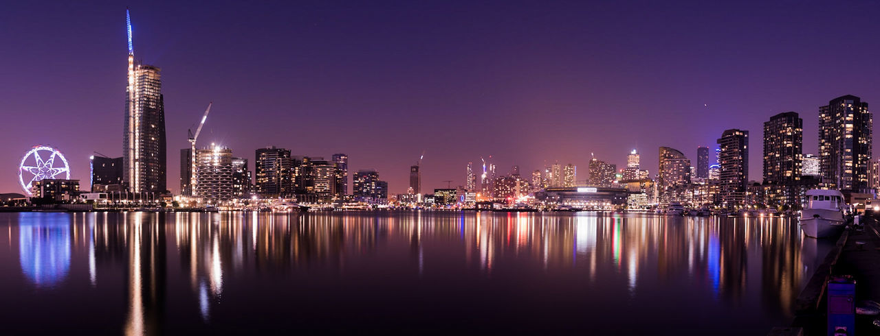 Illuminated buildings reflecting in river in city at night