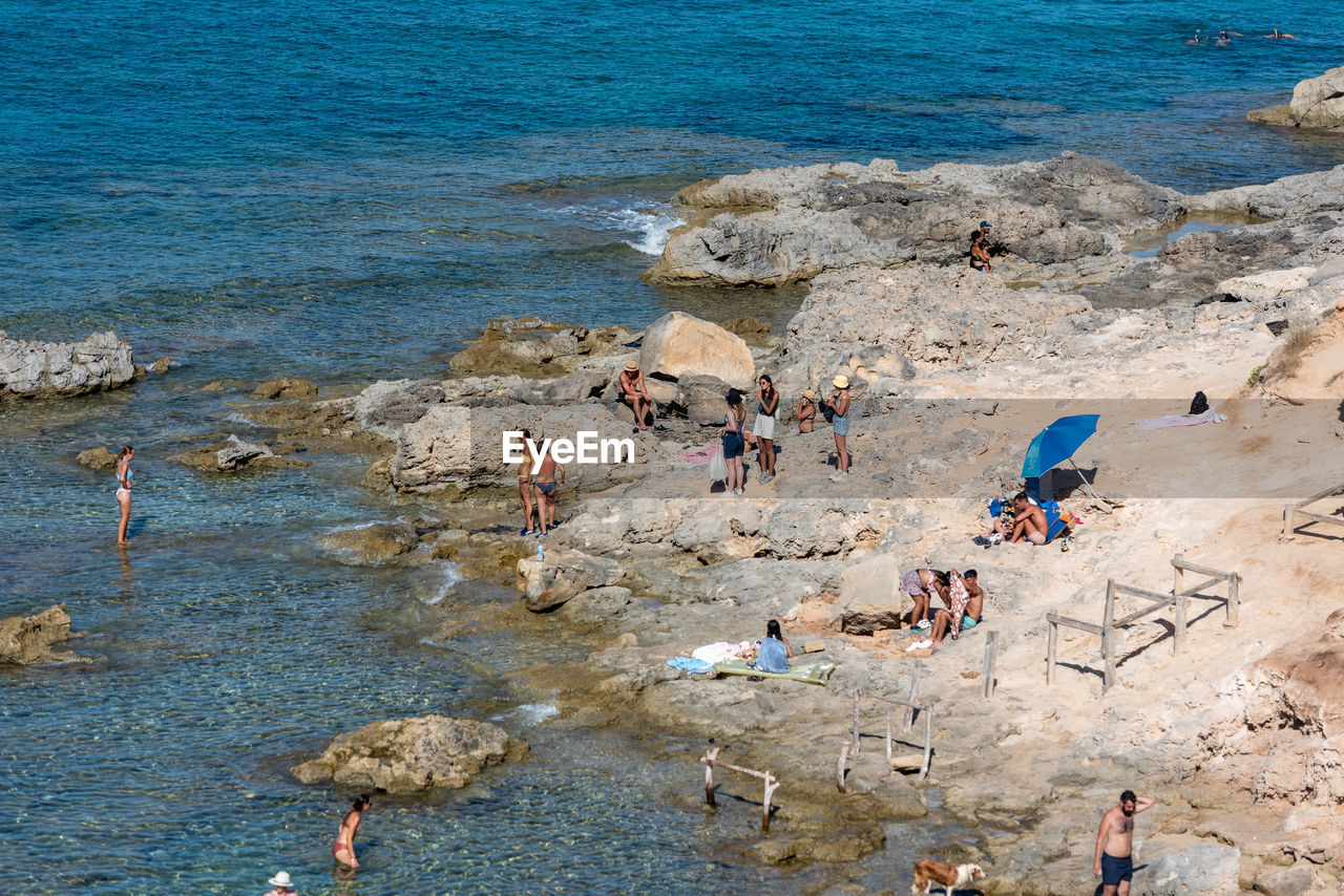 water, land, beach, sea, group of people, large group of people, high angle view, shore, coast, crowd, nature, body of water, vacation, leisure activity, trip, rock, holiday, day, sand, lifestyles, beauty in nature, men, women, scenics - nature, outdoors, sports, ocean, relaxation, travel, adult, tourist, summer